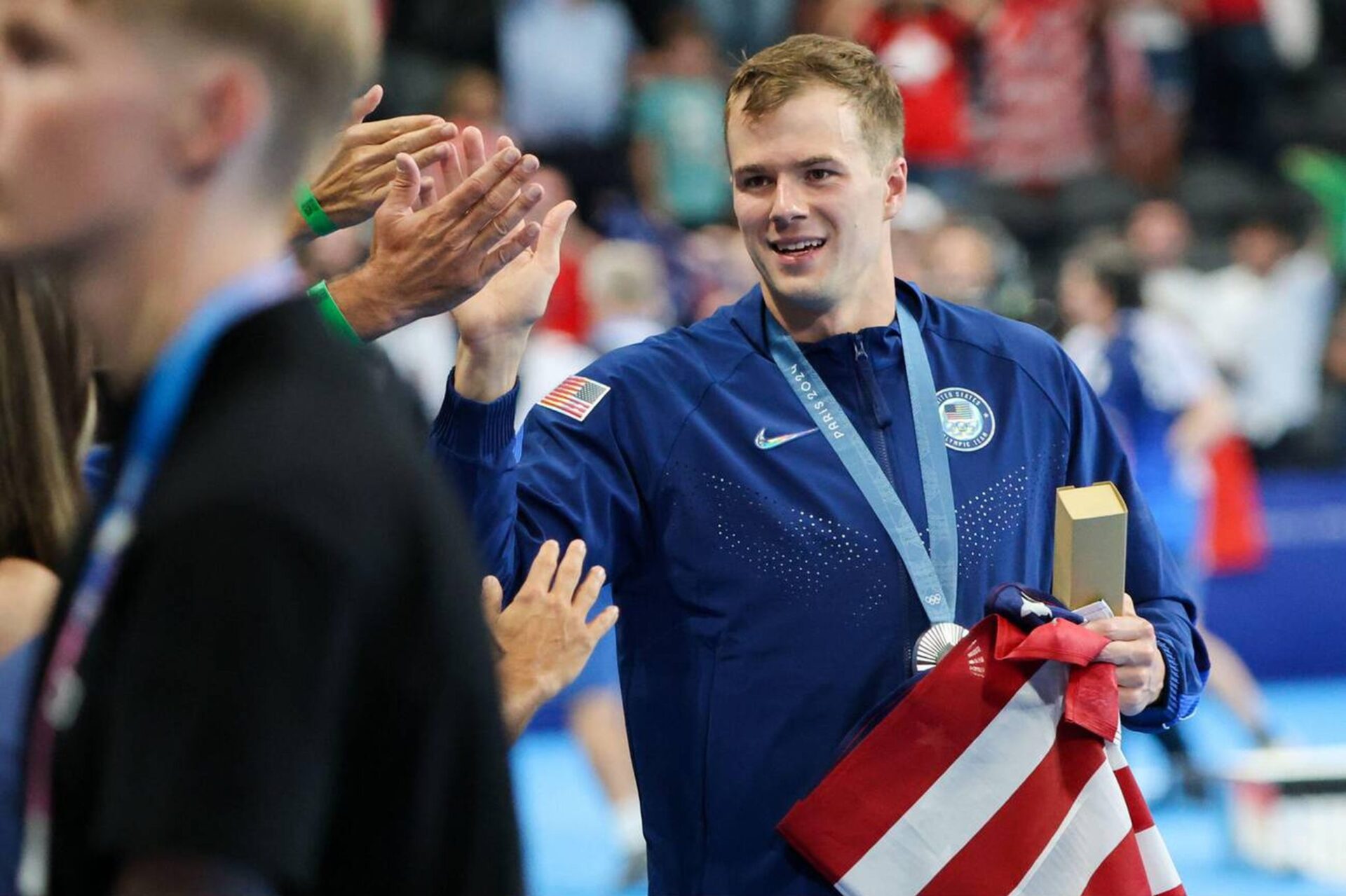 Nic Fink (USA) carries flag after his silver medal win in the men's 100-meter breaststroke medal ceremony during the Paris 2024 Olympic Summer Games at Paris La Défense Arena